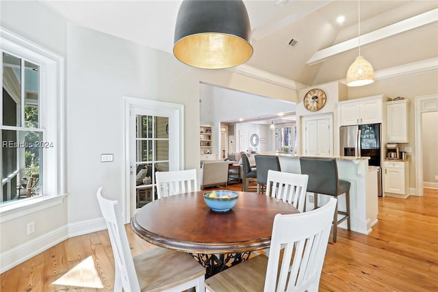 dining area with light hardwood / wood-style floors and vaulted ceiling with beams