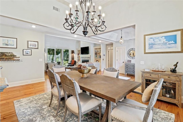 dining space with a chandelier, built in features, and light hardwood / wood-style floors