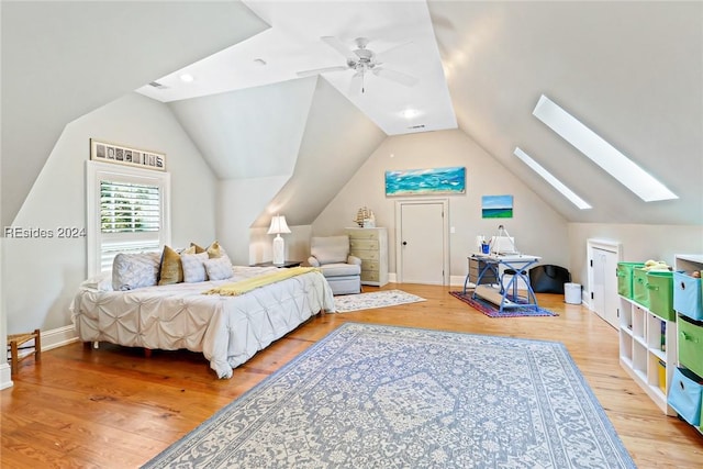 bedroom featuring ceiling fan, vaulted ceiling with skylight, and light hardwood / wood-style flooring