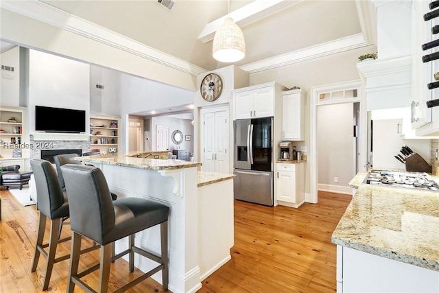 kitchen featuring white cabinetry, stainless steel fridge, light stone counters, and pendant lighting