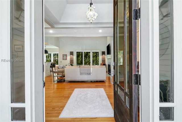 entrance foyer featuring a healthy amount of sunlight, vaulted ceiling, wood-type flooring, and a notable chandelier