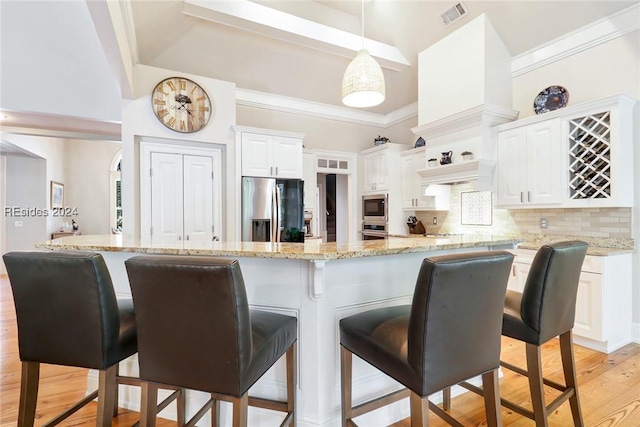 kitchen with appliances with stainless steel finishes, white cabinetry, backsplash, light stone counters, and decorative light fixtures