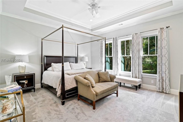 carpeted bedroom with a tray ceiling, ornamental molding, and ceiling fan