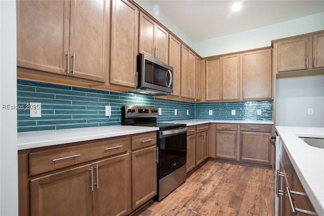 kitchen with tasteful backsplash, hardwood / wood-style floors, and stainless steel appliances