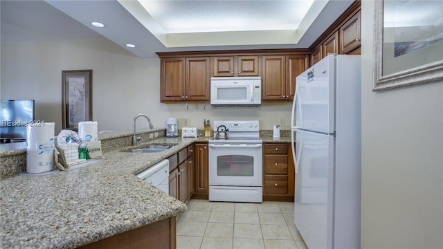 kitchen with sink, white appliances, light tile patterned floors, light stone countertops, and a raised ceiling