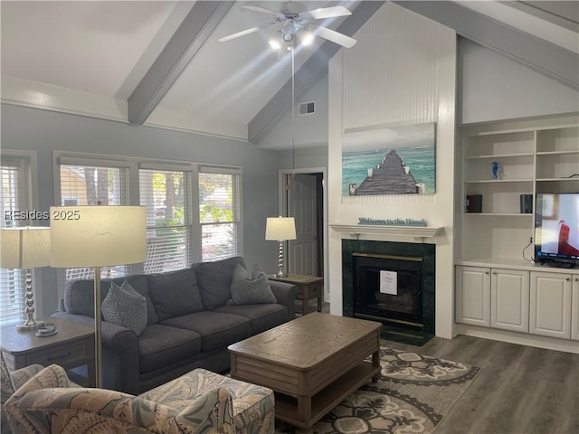 living room featuring dark hardwood / wood-style flooring, built in shelves, a fireplace, and a healthy amount of sunlight