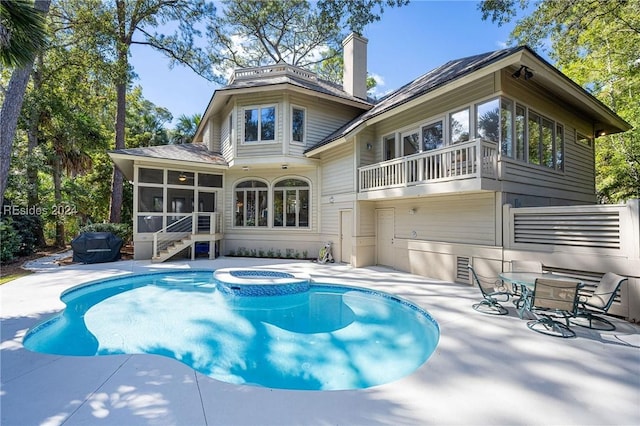 back of property featuring a swimming pool with hot tub, a patio, a sunroom, and a balcony