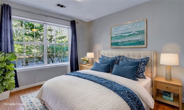 bedroom with hardwood / wood-style flooring and multiple windows