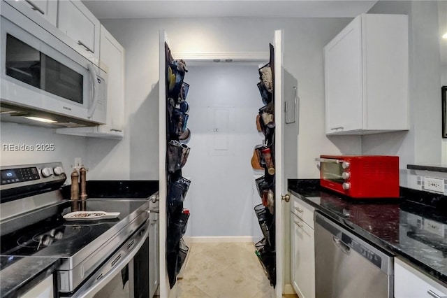 kitchen with appliances with stainless steel finishes, white cabinets, and dark stone counters