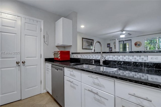 kitchen with tasteful backsplash, white cabinetry, sink, dark stone countertops, and stainless steel dishwasher