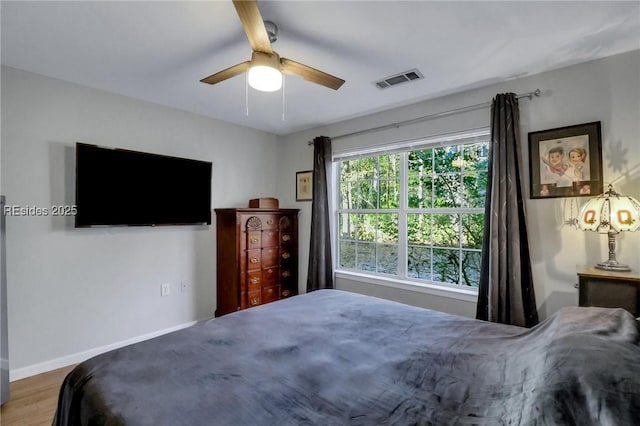 bedroom featuring multiple windows, hardwood / wood-style flooring, and ceiling fan