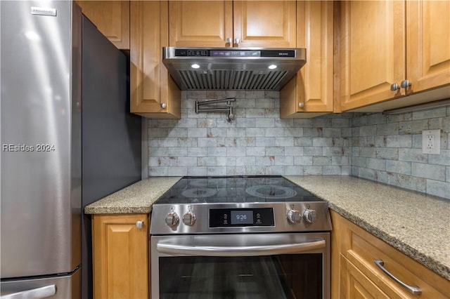 kitchen featuring ventilation hood, tasteful backsplash, light stone countertops, and stainless steel appliances