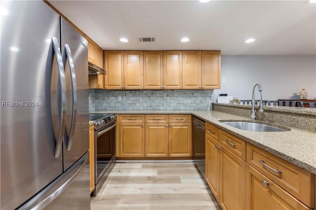 kitchen featuring sink, light hardwood / wood-style flooring, appliances with stainless steel finishes, light stone countertops, and decorative backsplash