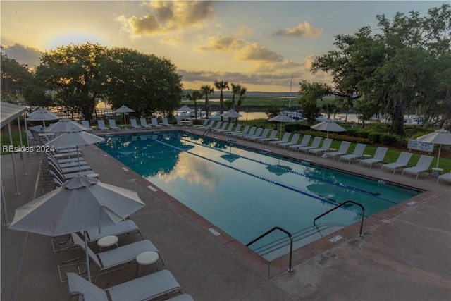 pool at dusk with a patio area