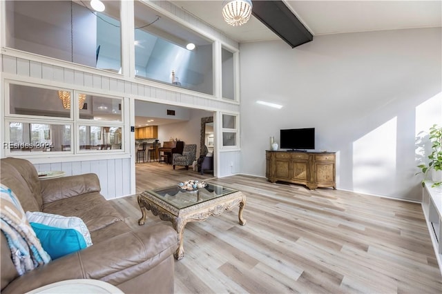 living room with beamed ceiling, high vaulted ceiling, and light hardwood / wood-style floors