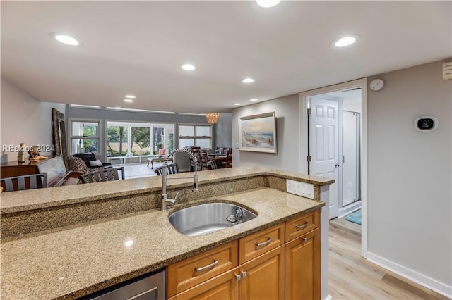 kitchen featuring light hardwood / wood-style floors, light stone countertops, and sink