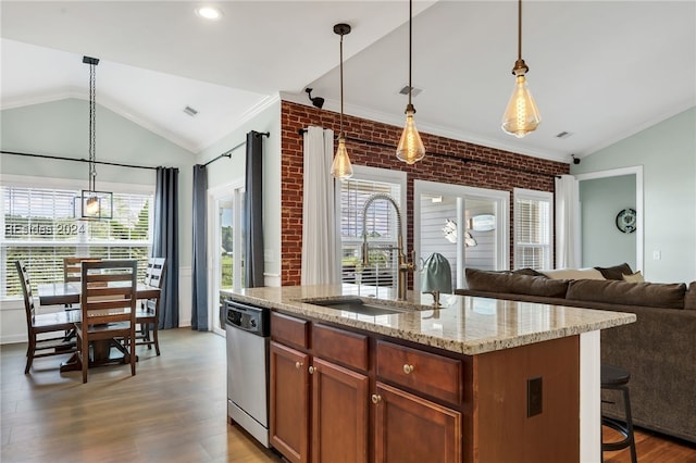 kitchen with pendant lighting, sink, dishwasher, an island with sink, and brick wall