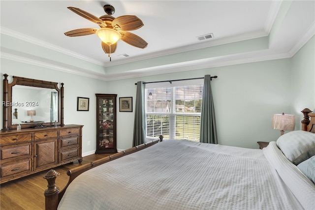 bedroom featuring crown molding, hardwood / wood-style flooring, a raised ceiling, and ceiling fan