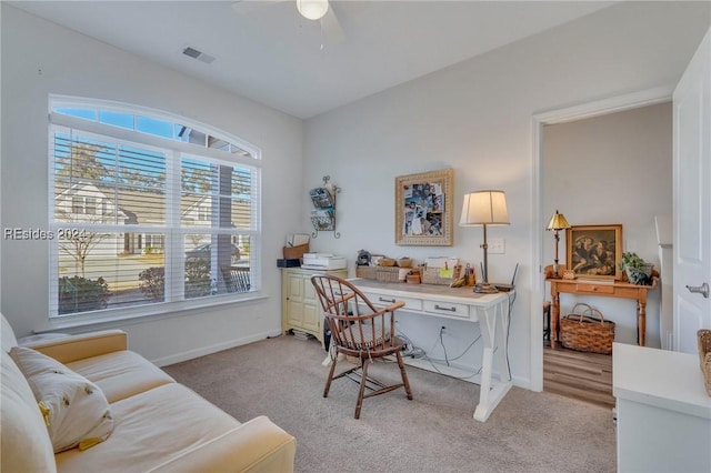 carpeted home office with built in desk and ceiling fan