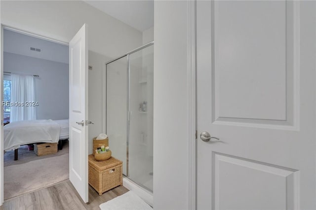 bathroom with hardwood / wood-style flooring and an enclosed shower