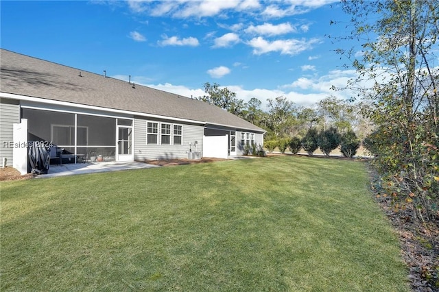 rear view of property featuring a yard, a sunroom, and a patio area