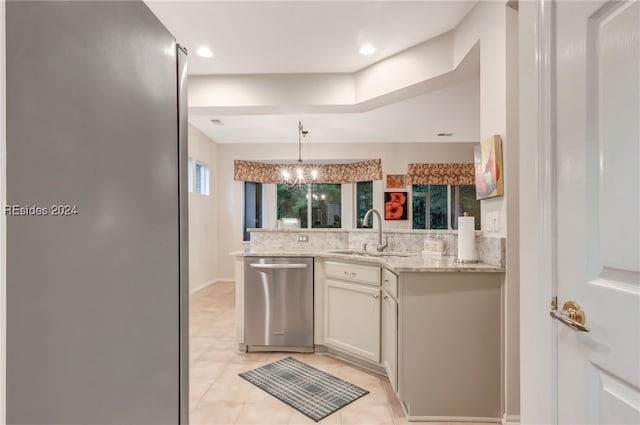 kitchen featuring sink, light stone counters, hanging light fixtures, stainless steel dishwasher, and white cabinets