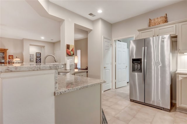 kitchen featuring stainless steel refrigerator with ice dispenser, light stone countertops, kitchen peninsula, and white cabinets