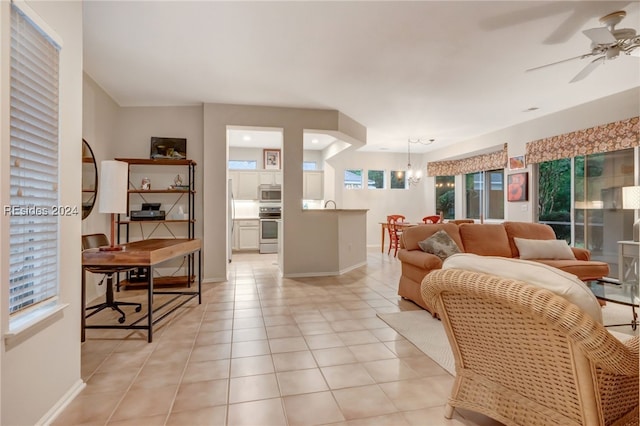 living room featuring light tile patterned flooring and ceiling fan with notable chandelier