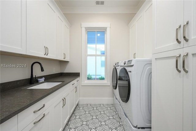 clothes washing area featuring cabinets, crown molding, sink, and washer and clothes dryer