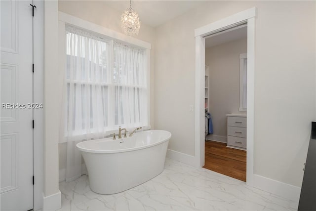 bathroom featuring a tub to relax in and a chandelier