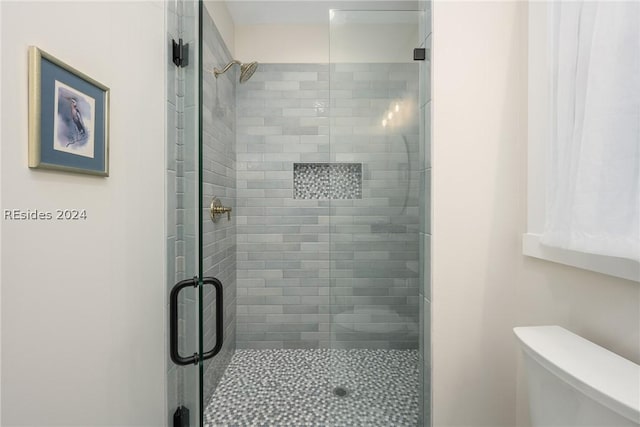 bathroom featuring walk in shower and toilet