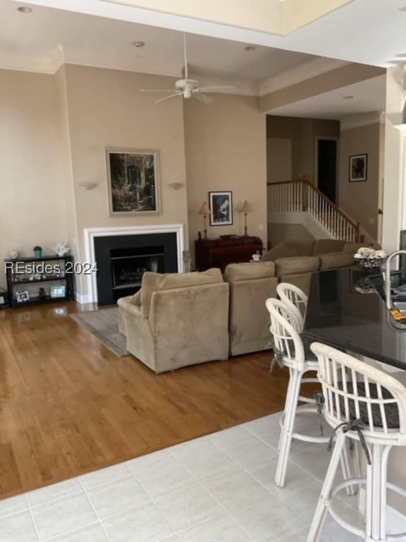 living room with ceiling fan, crown molding, and light wood-type flooring