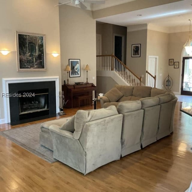 living room featuring hardwood / wood-style flooring, ceiling fan, and crown molding