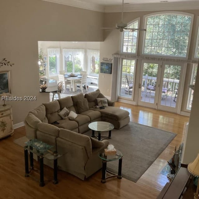 living room featuring a high ceiling, ornamental molding, hardwood / wood-style floors, and ceiling fan