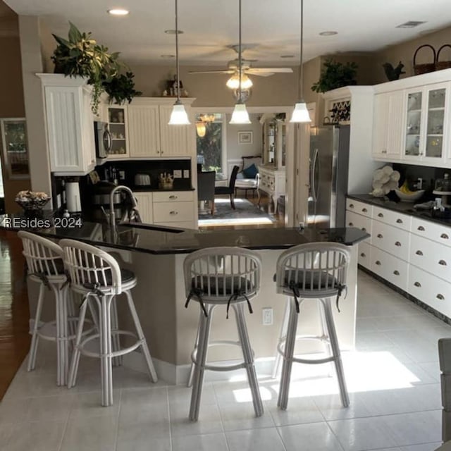 kitchen with pendant lighting, a kitchen bar, an island with sink, and appliances with stainless steel finishes