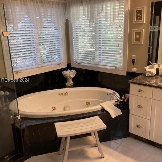 bathroom with tiled tub, vanity, and tile patterned floors