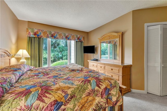 bedroom with light colored carpet, a textured ceiling, and a closet