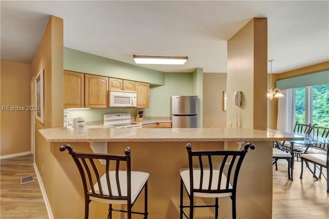 kitchen with stainless steel fridge, a kitchen breakfast bar, stove, kitchen peninsula, and light brown cabinets