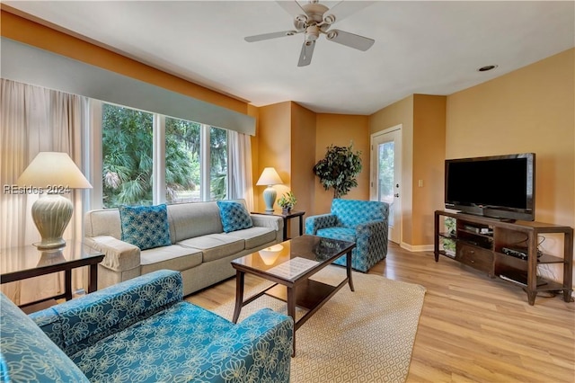 living room with ceiling fan, plenty of natural light, and light wood-type flooring