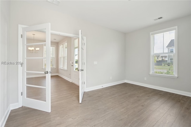 spare room featuring hardwood / wood-style flooring, a chandelier, and french doors