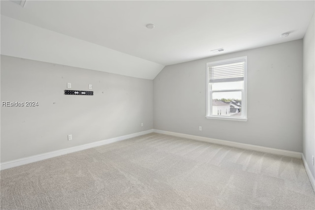 carpeted spare room featuring lofted ceiling