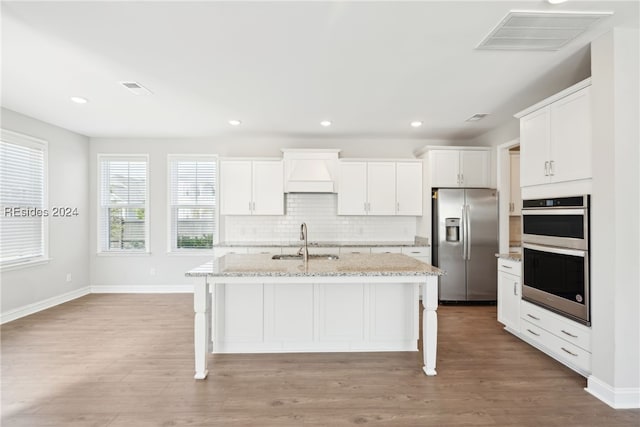 kitchen featuring a breakfast bar, sink, stainless steel appliances, a kitchen island with sink, and white cabinets