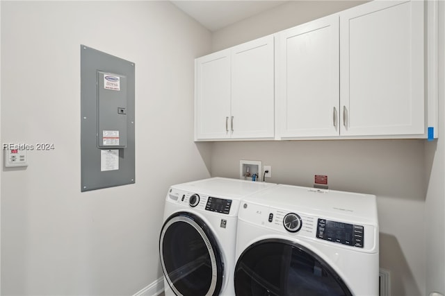 clothes washing area featuring cabinets, electric panel, and washing machine and dryer