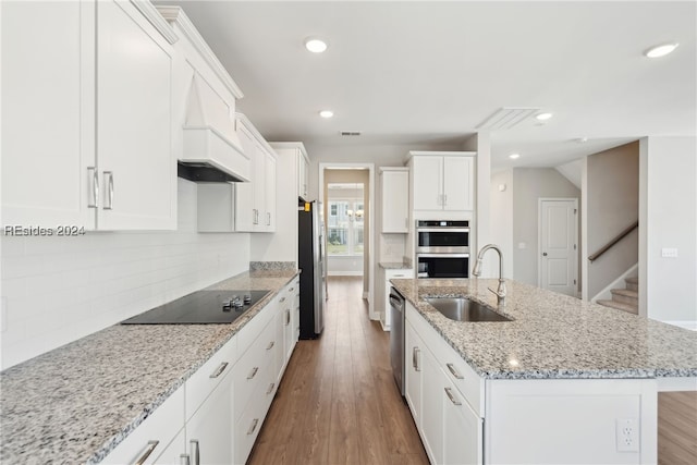 kitchen with sink, white cabinetry, light stone counters, a center island with sink, and stainless steel appliances