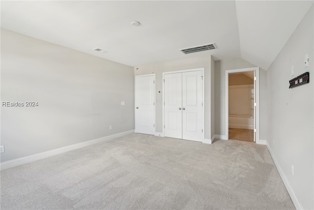 unfurnished bedroom featuring lofted ceiling, connected bathroom, and light carpet