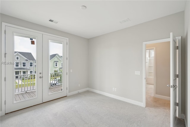 empty room featuring a wealth of natural light, light colored carpet, and french doors