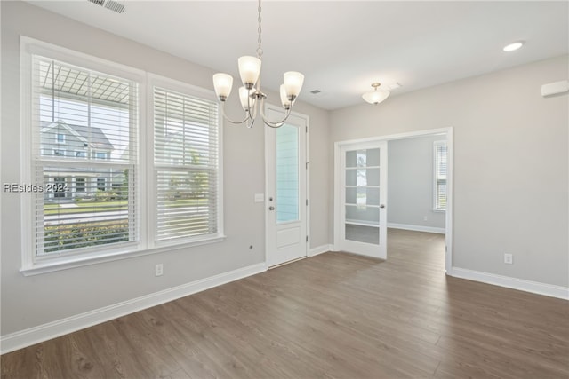 unfurnished dining area with a healthy amount of sunlight, hardwood / wood-style floors, and an inviting chandelier