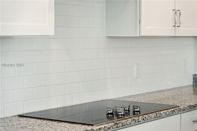 kitchen with tasteful backsplash, black electric cooktop, and white cabinets