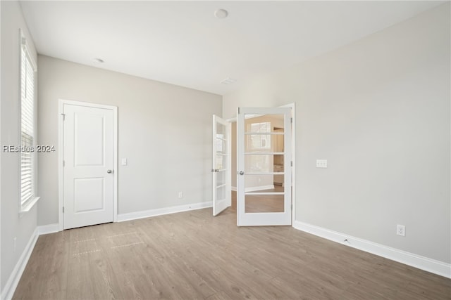 unfurnished room with a healthy amount of sunlight, light wood-type flooring, and french doors