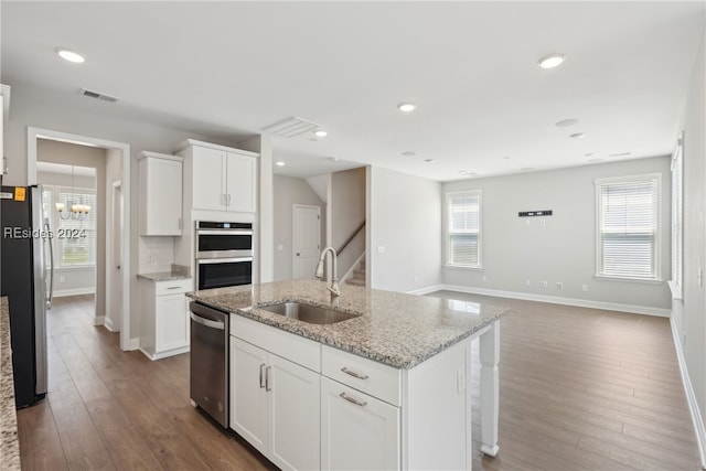 kitchen featuring sink, appliances with stainless steel finishes, a kitchen island with sink, light stone countertops, and white cabinets